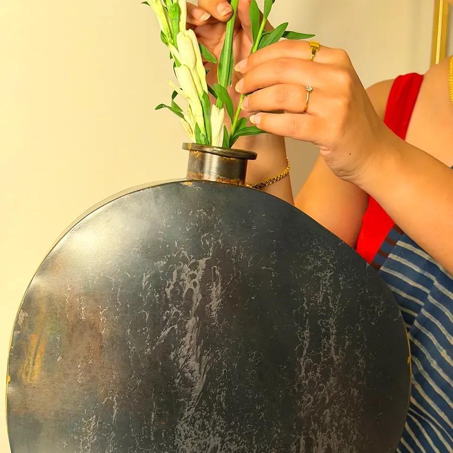 Tuberose stems being placed into a large round dark iron vase