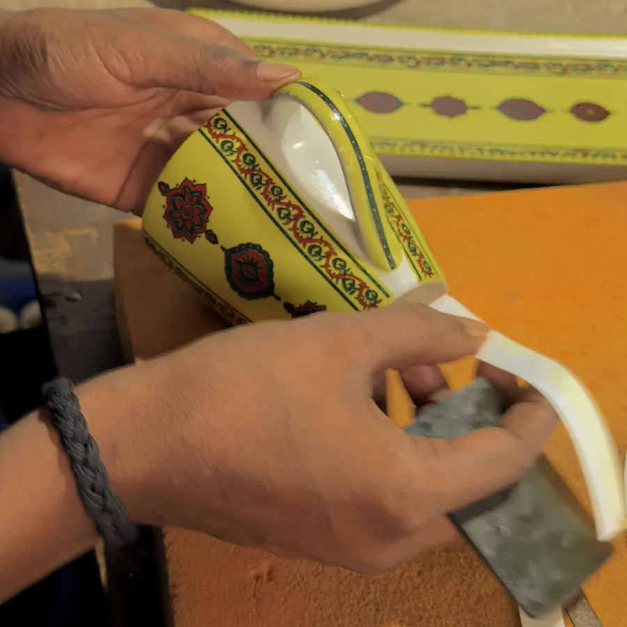 A printed decal being smoothed onto a glazed mug by hand