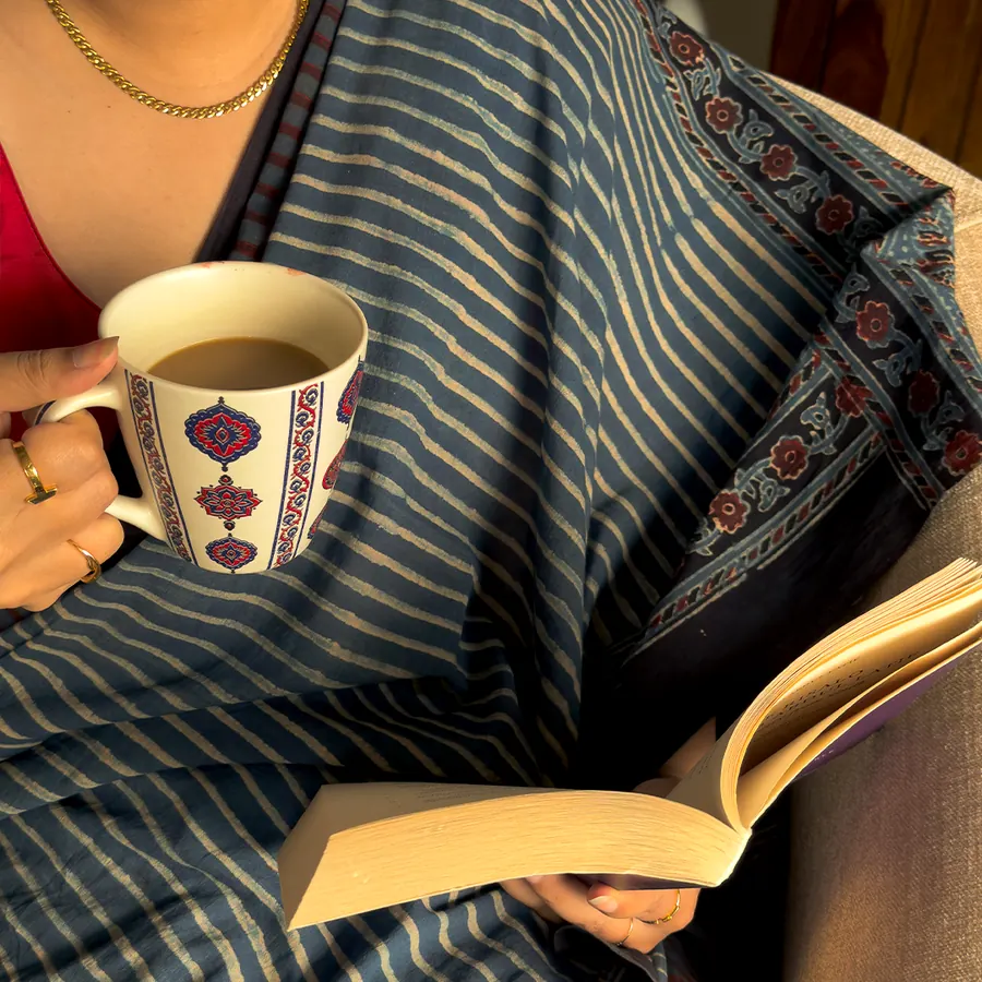 Reading with a mug, wrapped in an indigo Ajrakh shawl